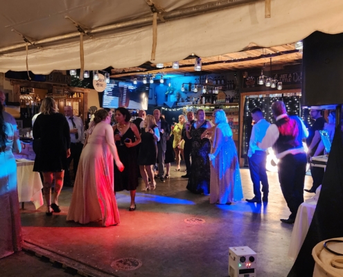 Wedding guests dance inside Rusty Nickel Brewing. Party lights set the scene in front of the dj.