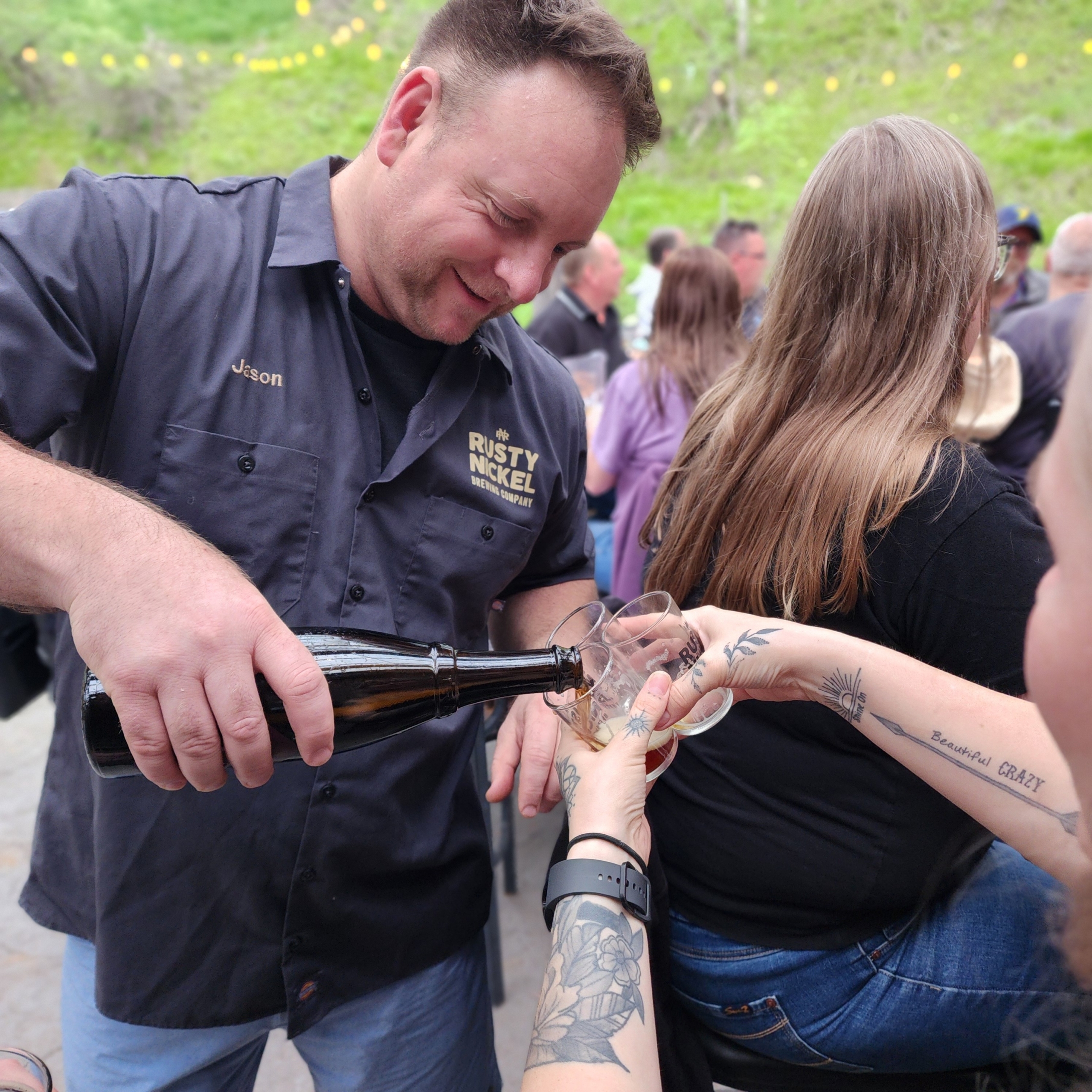 Owner of Rusty Nickel Brewing pours a guest of a sample of beer from a bottle