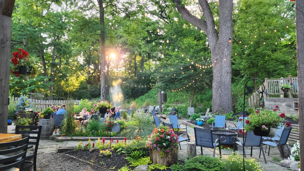 Sunset in the beer garden. large trees and plants surround the gardens. A fountain showers over the pond.