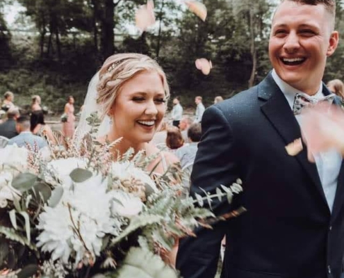 a newly married bride and groom are showered in flower petals as they walk down the aisle