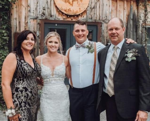 a bride and groom poses for photos with family in front of Rusty Nickel Brewing's tasting room.