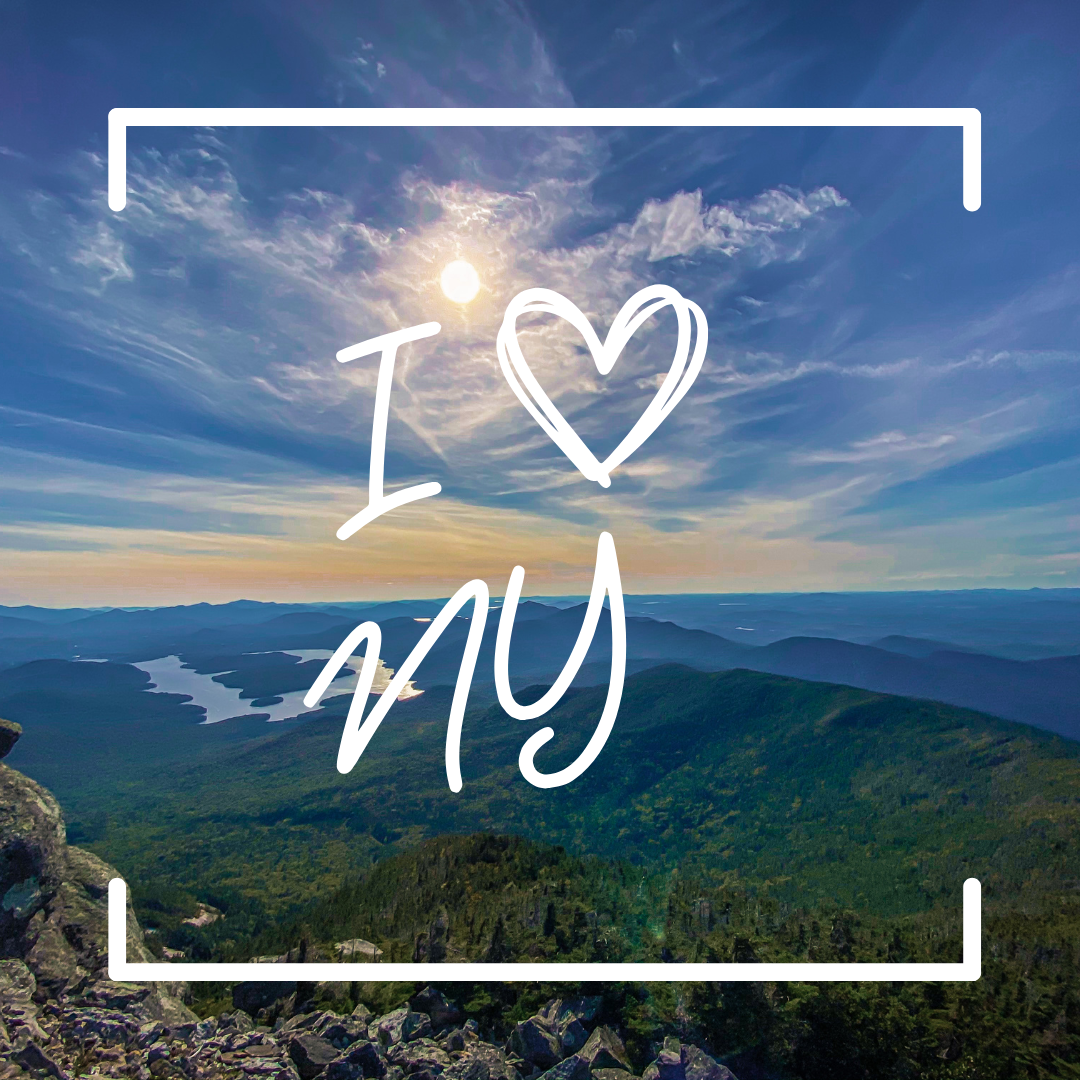 A view of Adirondack Park from the peak of Whiteface Mountain on a sunny summer day. Text reads "I heart NY"