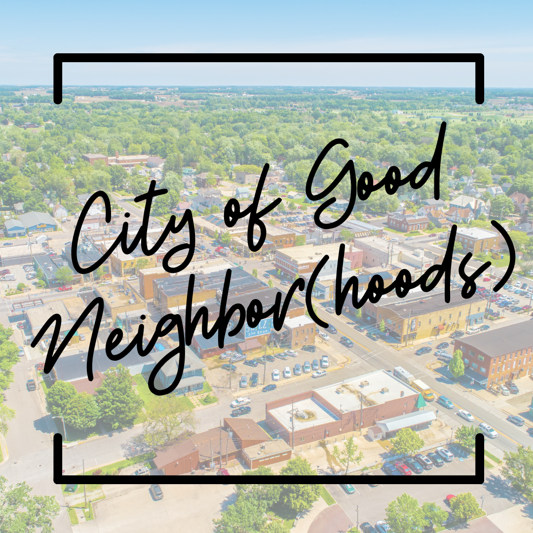 An aerial view of a small town. Streets are lined with buildings and trees. Text says "City of Good Neighbor(hoods)"
