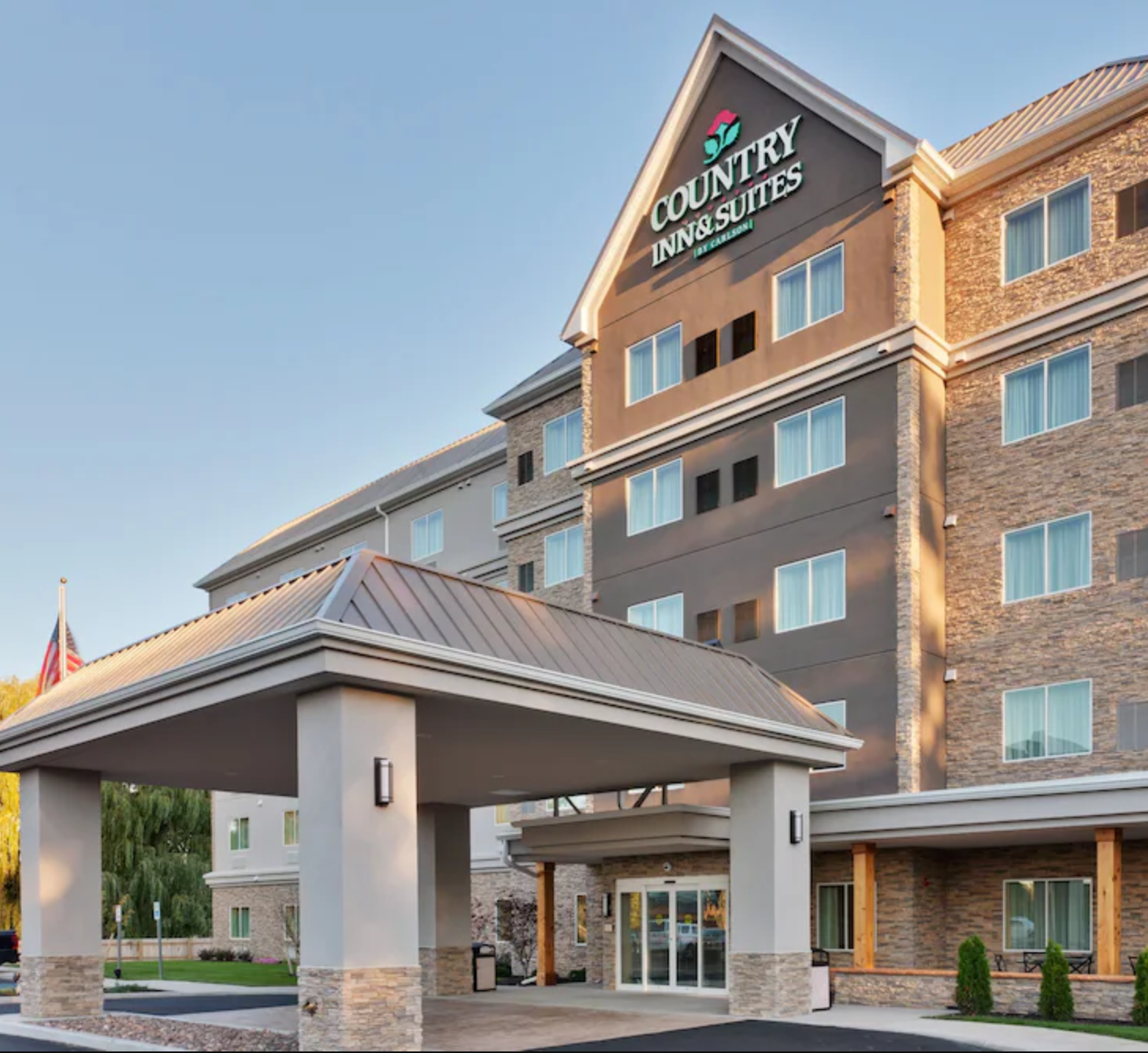 Exterior view of Country Inn and Suites in West Seneca, NY. A large building with a covered, drive lane at the front doors.