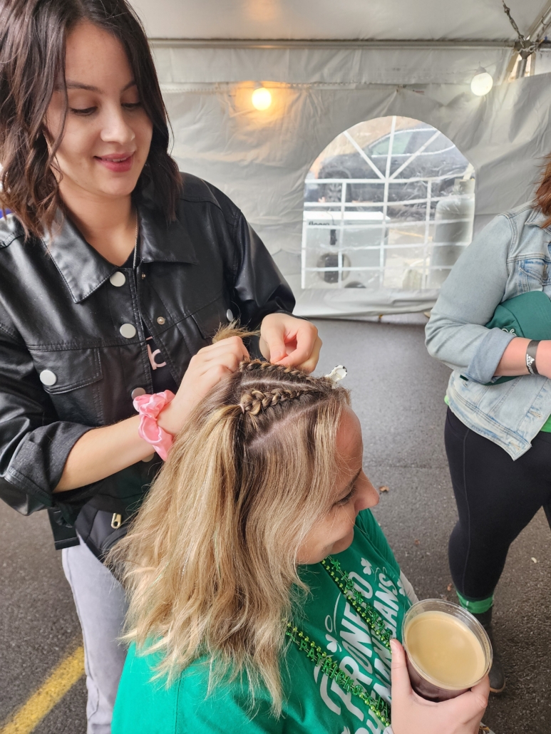 Person styling another's hair outdoors.
